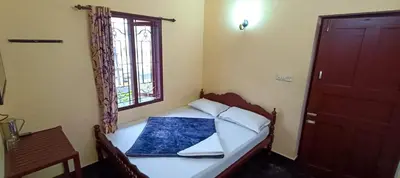 a small bedroom with a bed and a window at Swarna Tourist home Munnar in Munnar