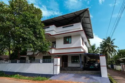 a white house with a car parked in front of it at Nest Villa - A Homely Heaven Near the Skies in Nedumbassery