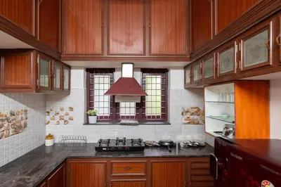 a kitchen with wooden cabinets and a stove top oven at Nest Villa - A Homely Heaven Near the Skies in Nedumbassery