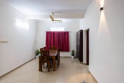 a dining room with a table and a red curtain at Nest Villa - A Homely Heaven Near the Skies in Nedumbassery