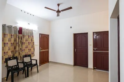a living room with two chairs and a ceiling fan at Nest Villa - A Homely Heaven Near the Skies in Nedumbassery