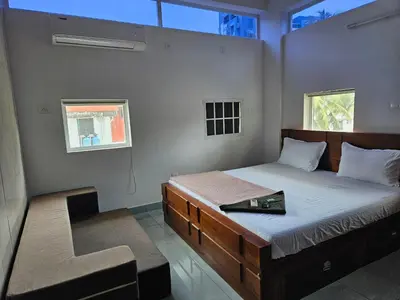 a bedroom with a bed and a chair in it at Yogis Stay in Kozhikode