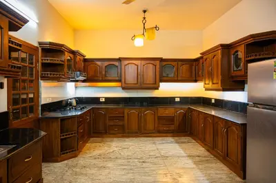 a large kitchen with wooden cabinets and black counter tops at Puzhayoram holiday home, Aluva in Alwaye