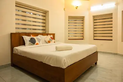 a bedroom with a large bed in a room with windows at Puzhayoram holiday home, Aluva in Alwaye