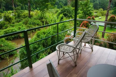 two chairs and a table on a balcony overlooking a river at River Wild holiday home in Athirappilly