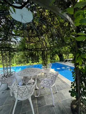 a table and chairs under a pergola next to a pool at River Wild holiday home in Athirappilly