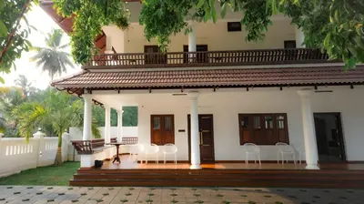 a porch of a house with white chairs at Tamarind Heritage Holiday Home in Angamali