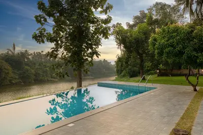 a swimming pool with a view of a river at Theeram Riverside Holiday Home in Māla