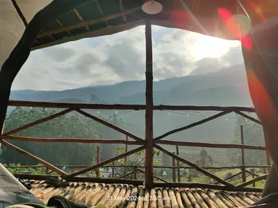 a view from the inside of a tent looking at a mountain at Hazy Mount Vattavada in Kottakamboor