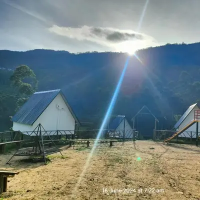 two white barns with the sun shining behind them at Hazy Mount Vattavada in Kottakamboor