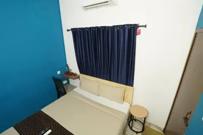 a small room with a couch and a blue curtain at Twinn Waves By Atmos in Kozhikode