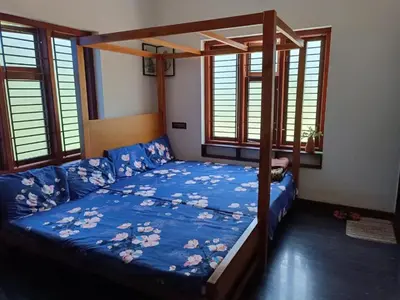 a bedroom with a canopy bed with a blue comforter at Shruthi's Aarohi-Nature's Retreat Homestay in Kannur