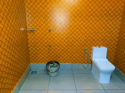 a bathroom with a toilet and a trash can at Merlys Fruit Garden in Cochin