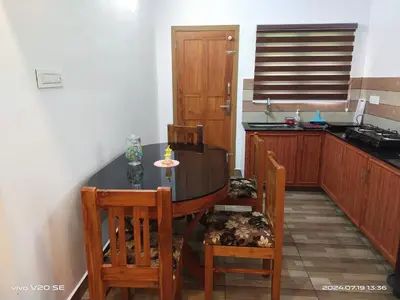 a kitchen with a table and chairs in a kitchen at Merlys Fruit Garden in Cochin