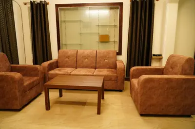 a living room with two chairs and a couch and a table at Meridian Rooms and Service Apartment in Mysore