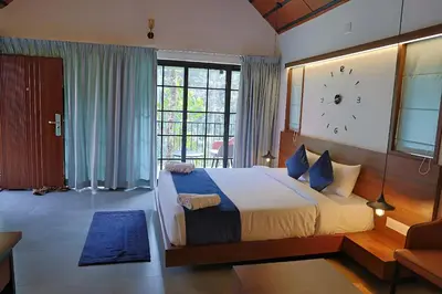 a bedroom with a large bed and a clock on the wall at Bay View Suites, Vythiri, Wayanad in Wayanad