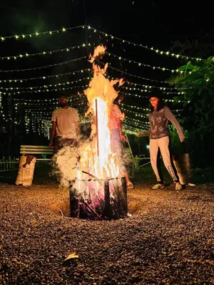 a woman is standing next to a bonfire at night at Bay View Suites, Vythiri, Wayanad in Wayanad