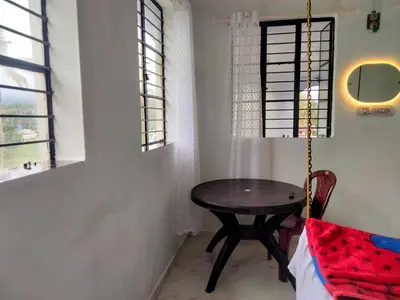 a dining room with a table and two windows at JK Home stay in Sultan Bathery