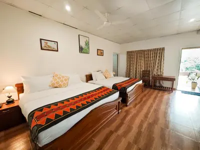 a bedroom with two beds and a desk and a window at Ibex Resorts, Valparai Mistly in Vālpārai