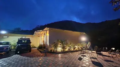 a house with a car parked in front of it at Ibex Resorts, Valparai Mistly in Vālpārai
