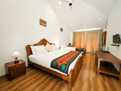 a bedroom with a large bed and a desk at Ibex Resorts, Valparai Mistly in Vālpārai