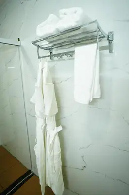 a bathroom with white towels hanging on a rack at Coorg Orange Blossom Resort and Spa in Suntikoppa