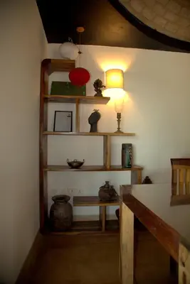 a room with shelves and a table with a lamp at O'Land Wilderness Lodge in Kolakambe