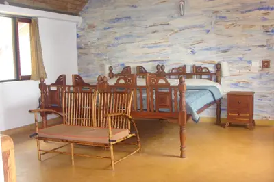 a bedroom with a bed and a stone wall at O'Land Wilderness Lodge in Kolakambe
