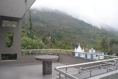 a balcony with a table and a view of a mountain at Misty Meadows in Kodaikānāl