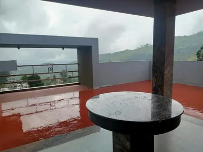 a table on top of a balcony with a view at Misty Meadows in Kodaikānāl