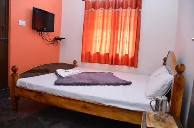 a bedroom with a bed and a tv and a window at Misty Meadows in Kodaikānāl
