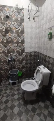 a bathroom with a toilet in a tiled room at Misty Meadows in Kodaikānāl