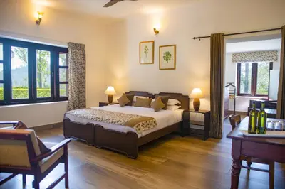 a bedroom with a bed and two tables and windows at Sinna Dorai's Rotti Kadai Bungalow in Vālpārai