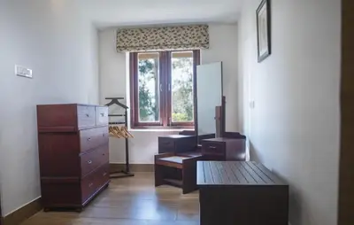 a room with a desk and a dresser and a window at Sinna Dorai's Rotti Kadai Bungalow in Vālpārai