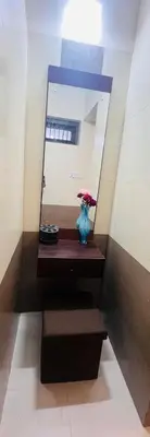 a mirror and a vase with flowers on a shelf at Meadows Serene Retreat in Kannur