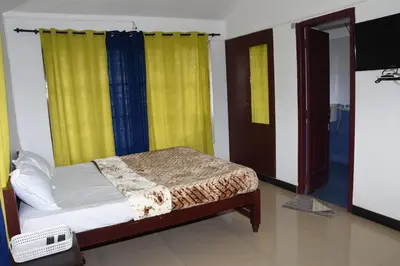 a bedroom with a bed with yellow curtains and a television at Elk Hill Palace in Ooty