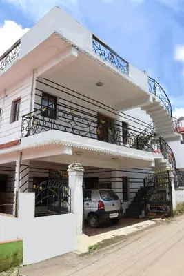 a white house with a car parked in front of it at Elk Hill Palace in Ooty