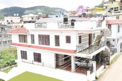 a white house with a staircase in a city at Elk Hill Palace in Ooty