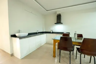 a kitchen with a sink and a table and chairs at Span Avenue in Kozhikode