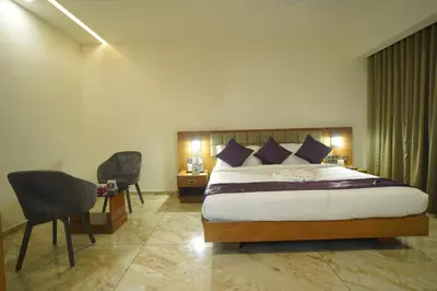a bedroom with a bed and a desk and chairs at Hotel Devalokam in Trittāla