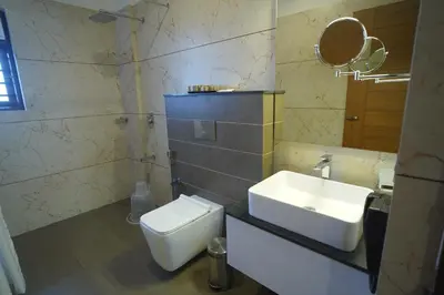 a bathroom with a sink and a toilet and a mirror at Hotel Devalokam in Trittāla