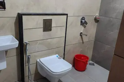a bathroom with a toilet and a red trash can at Nambiaparambil Serviced Villa in Kakkayam