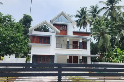 a white house with palm trees in front of it at Nambiaparambil Serviced Villa in Kakkayam