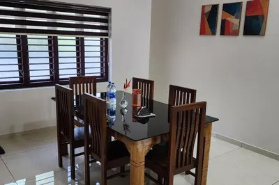 a dining room table with four chairs and a black table at Nambiaparambil Serviced Villa in Kakkayam