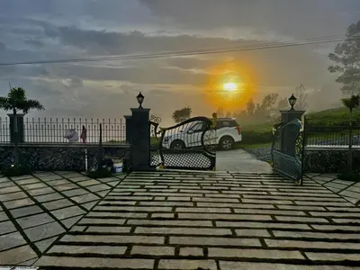 a car parked in a driveway with a sunset in the background at The Misty Valley in Kodanād