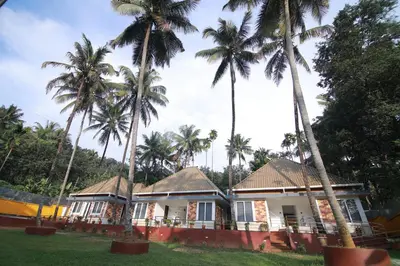a house with palm trees in front of it at PitStop21 in Athirappilly