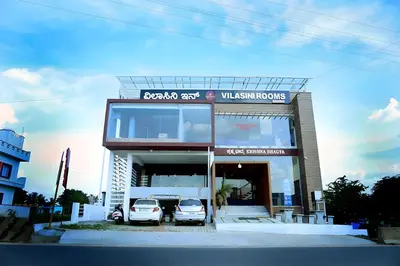two cars parked in front of a building at Vilasini Inn in Maddūr