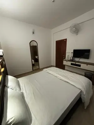 a bedroom with a white bed and a flat screen tv at casa wayn homestay in Sultan Bathery