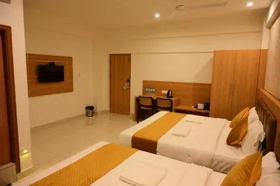a hotel room with two beds and a television at Bimba Hotels in Mysore