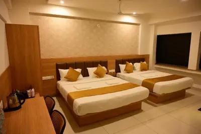 a hotel room with two beds and a television at Bimba Hotels in Mysore